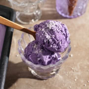 Two scoops of ube ice cream in a bowl with a spoon.
