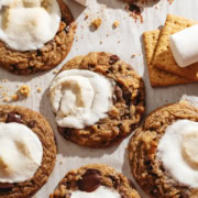 Several chocolate chip s'mores cookies scattered on parchment paper.