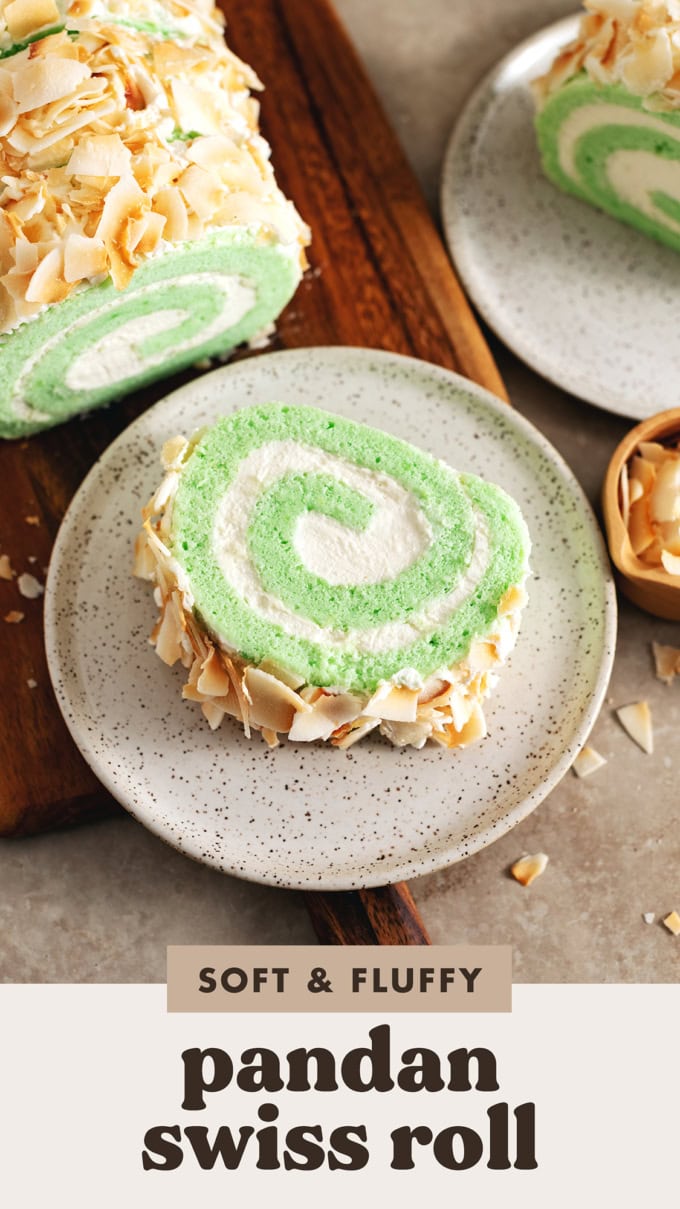 A slice of pandan swiss roll on a plate next to other slices of cake.