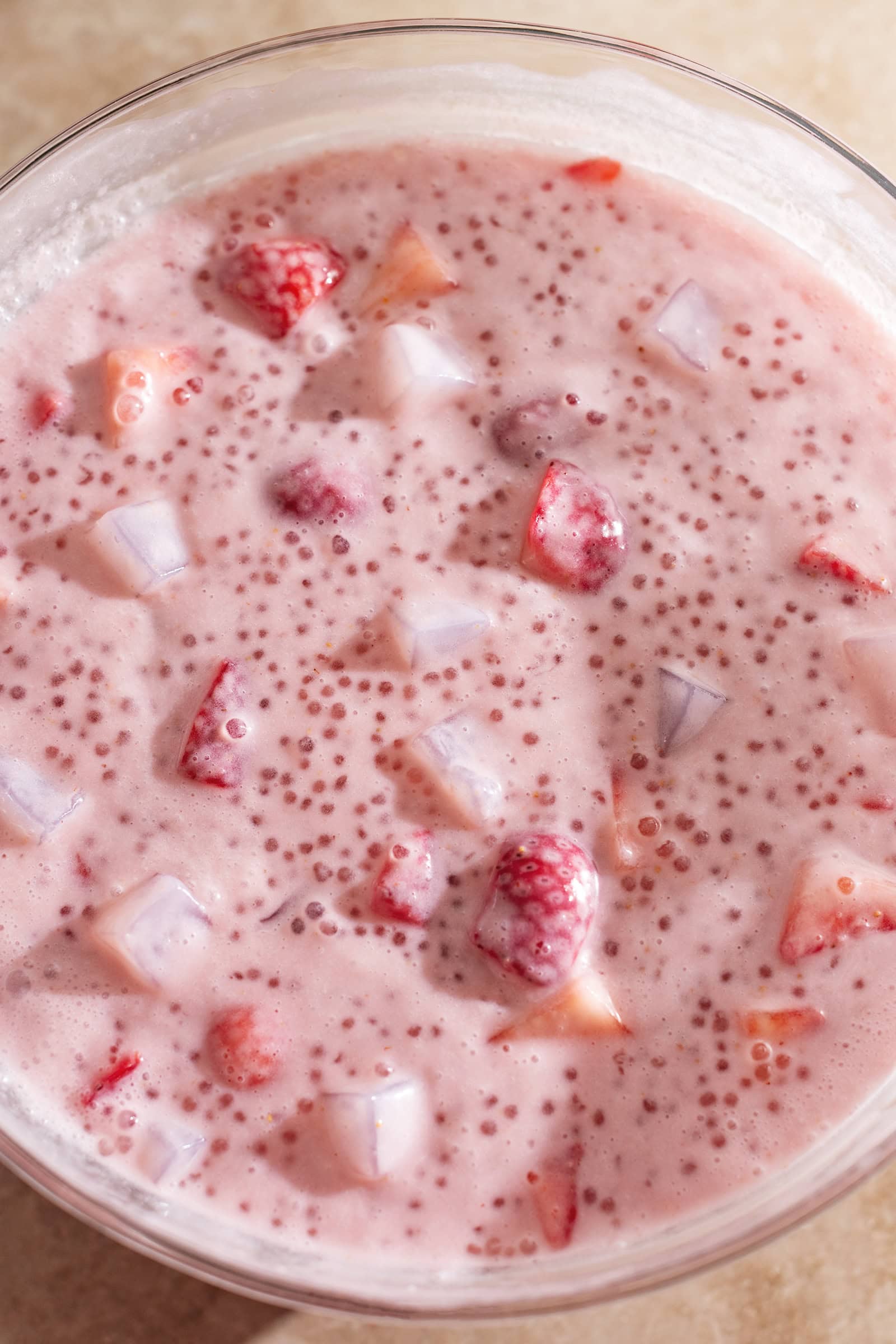 Overhead view of a big bowl of strawberry sago studded with strawberry chunks and coconut jellies.