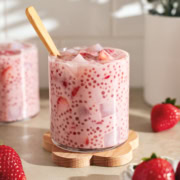 A glass cup filled with strawberry sago surrounded by strawberries.