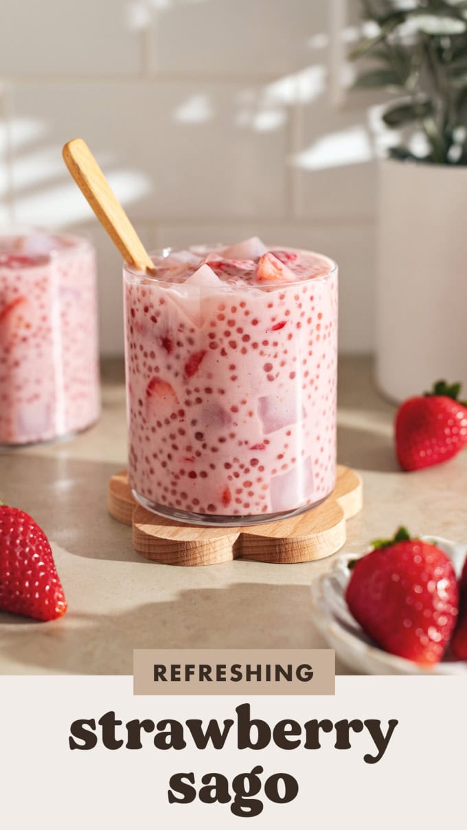 A glass cup filled with strawberry sago surrounded by strawberries.