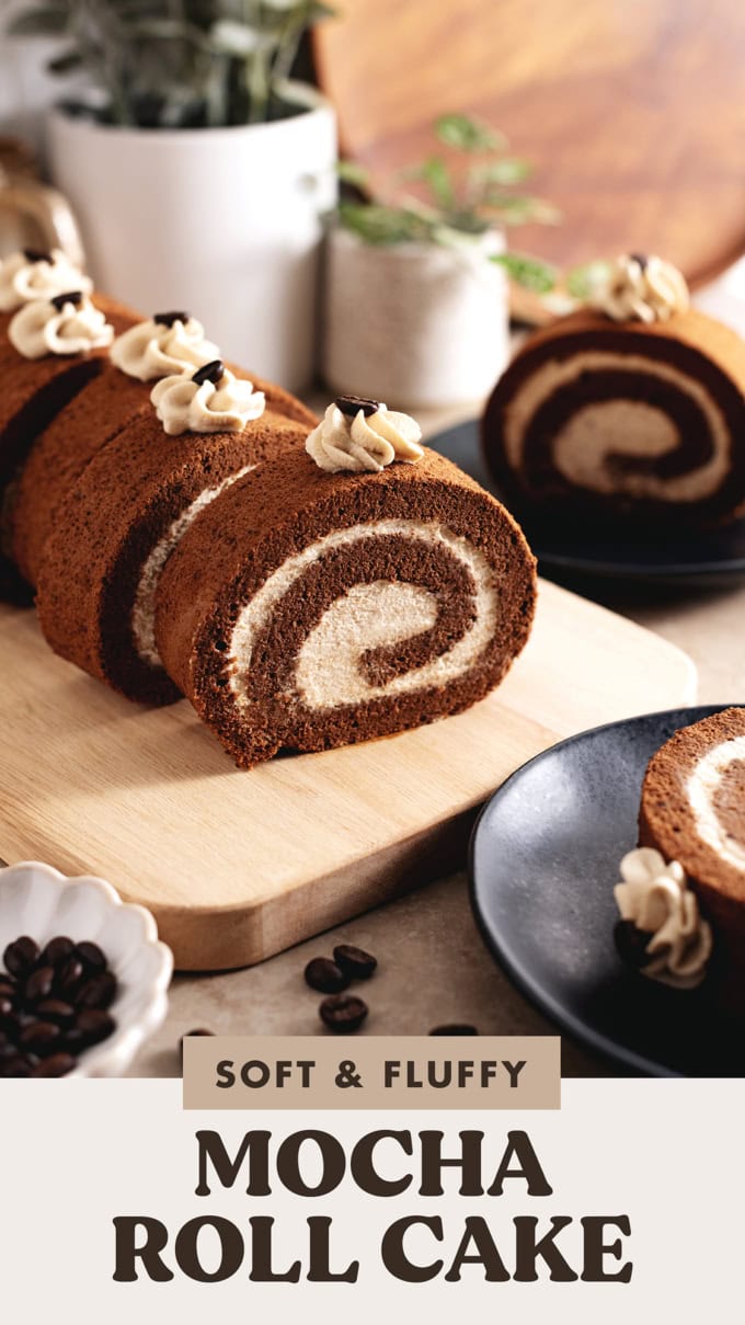 Slices of mocha roll cake on a wooden platter with coffee beans scattered in front of them.