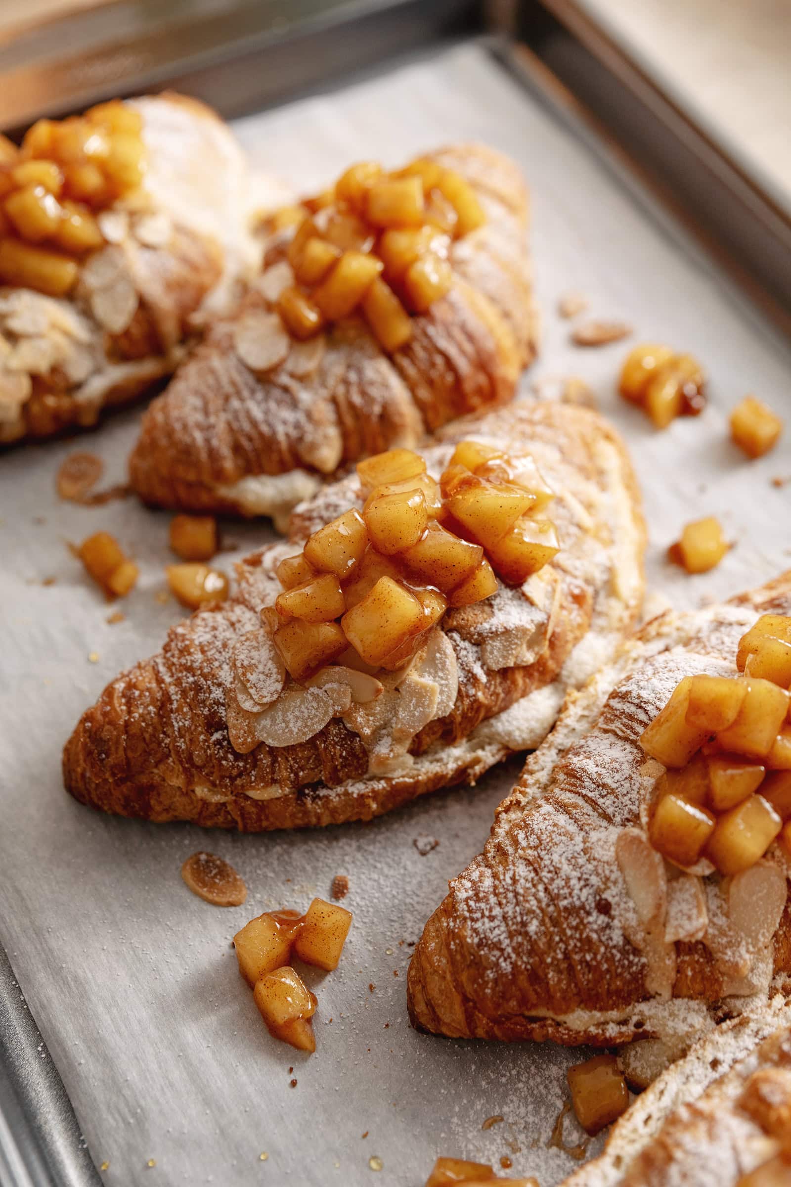 Apple pie almond croissants topped with apple pie filling on a baking tray.