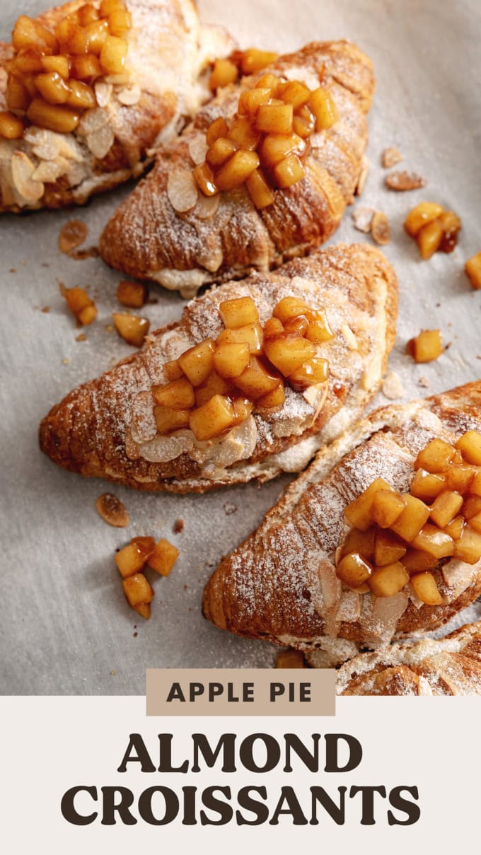 Several apple pie almond croissants lined up on parchment paper.