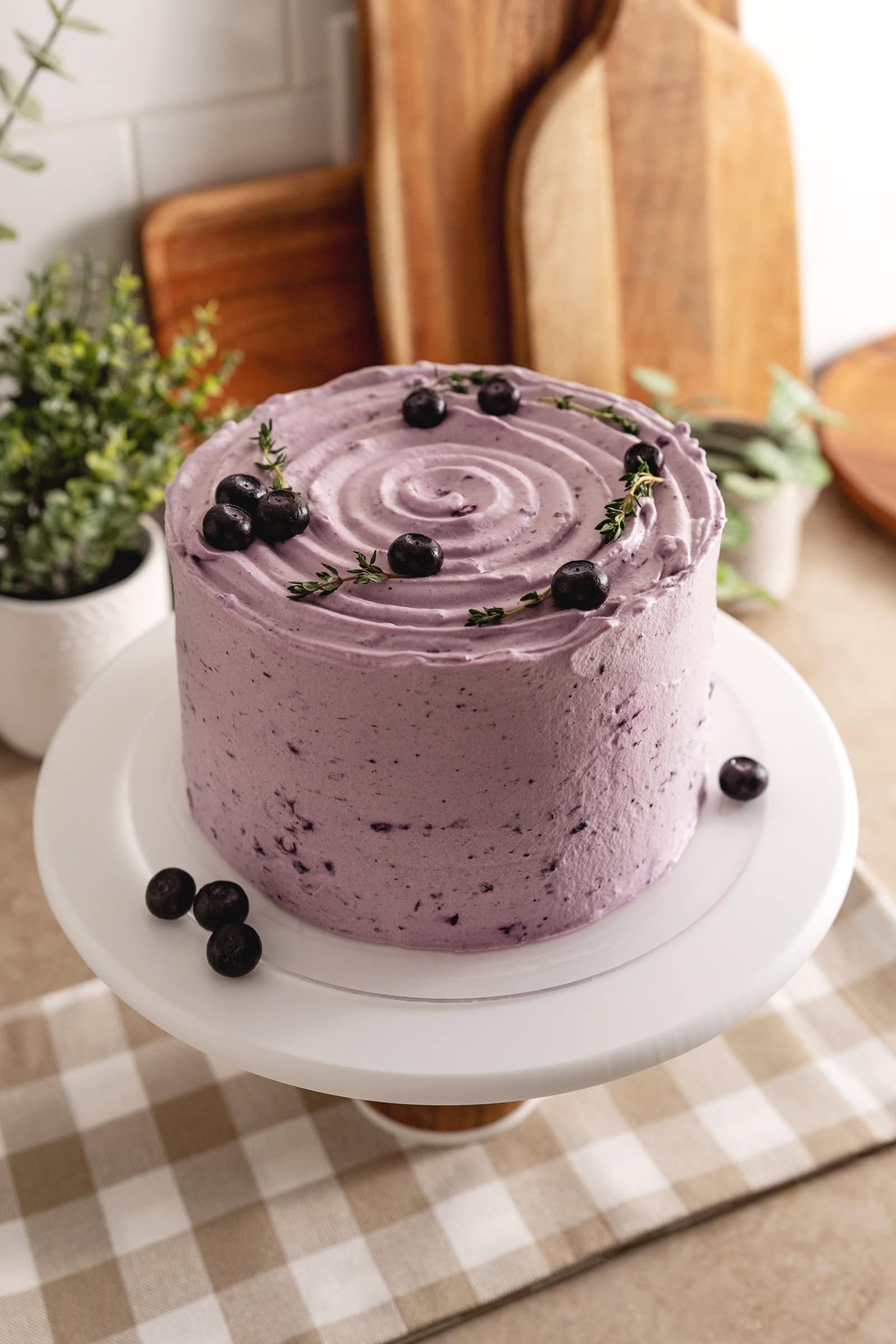 A whole blueberry chiffon cake on a cake stand.