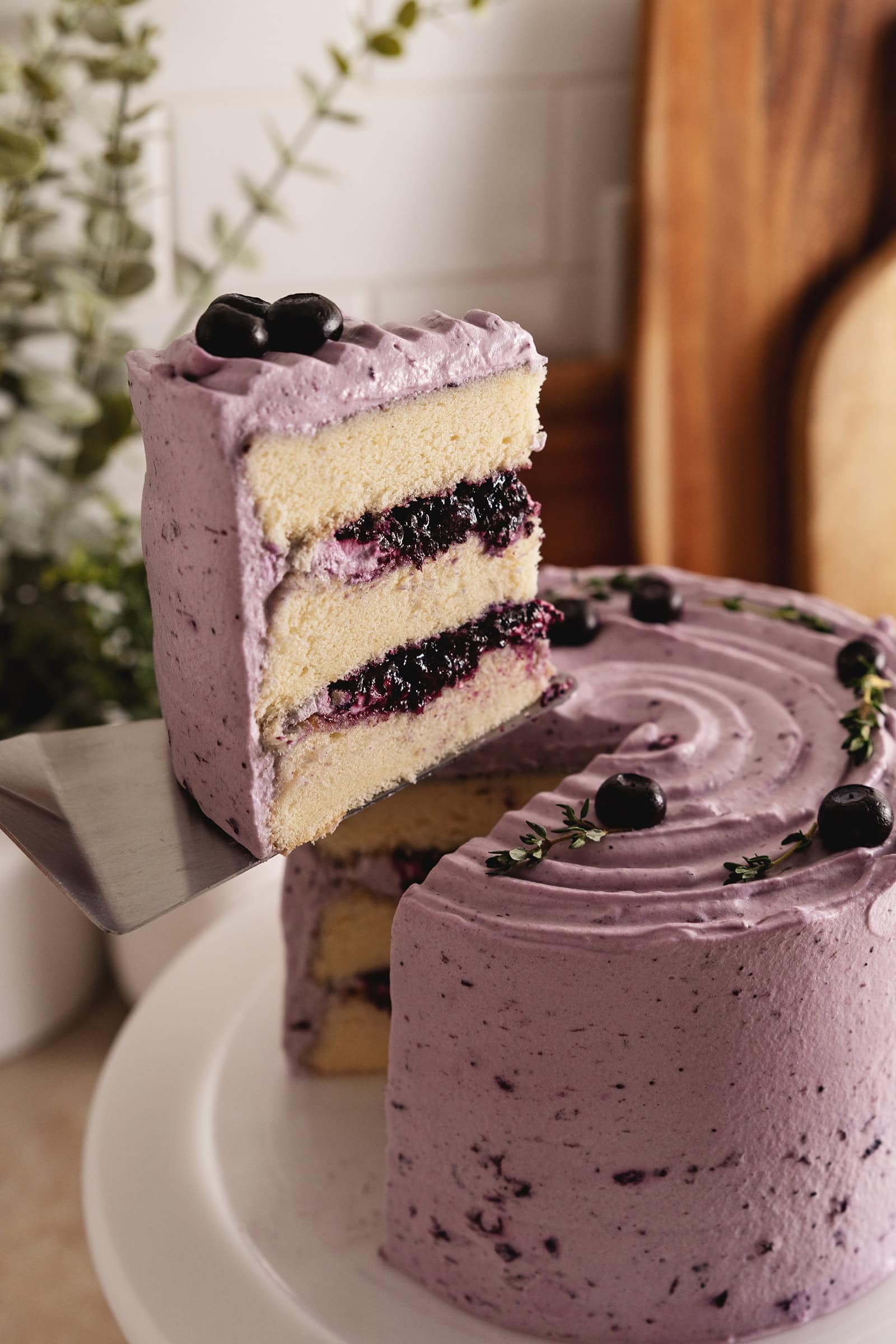 A slice of blueberry chiffon cake lifted from the rest of the cake with a cake server.