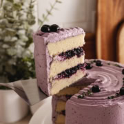 A slice of blueberry chiffon cake lifted from the rest of the cake with a cake server.
