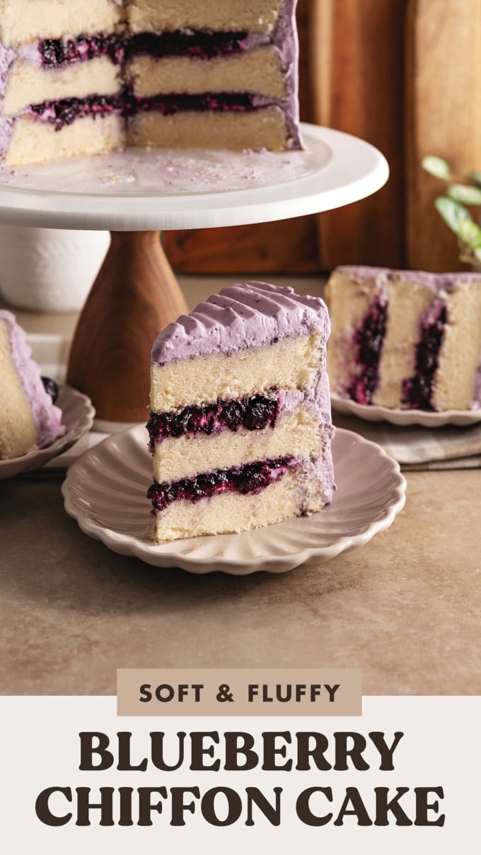 Close-up of a slice of blueberry chiffon cake on a plate in front of a cake stand.