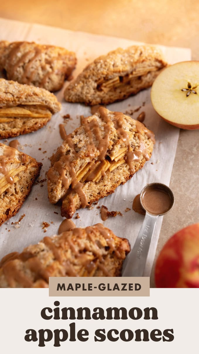 Cinnamon apple scones on parchment paper with a spoonful of icing next to them.