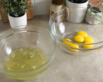 Two mixing bowls filled with egg whites and egg yolks.
