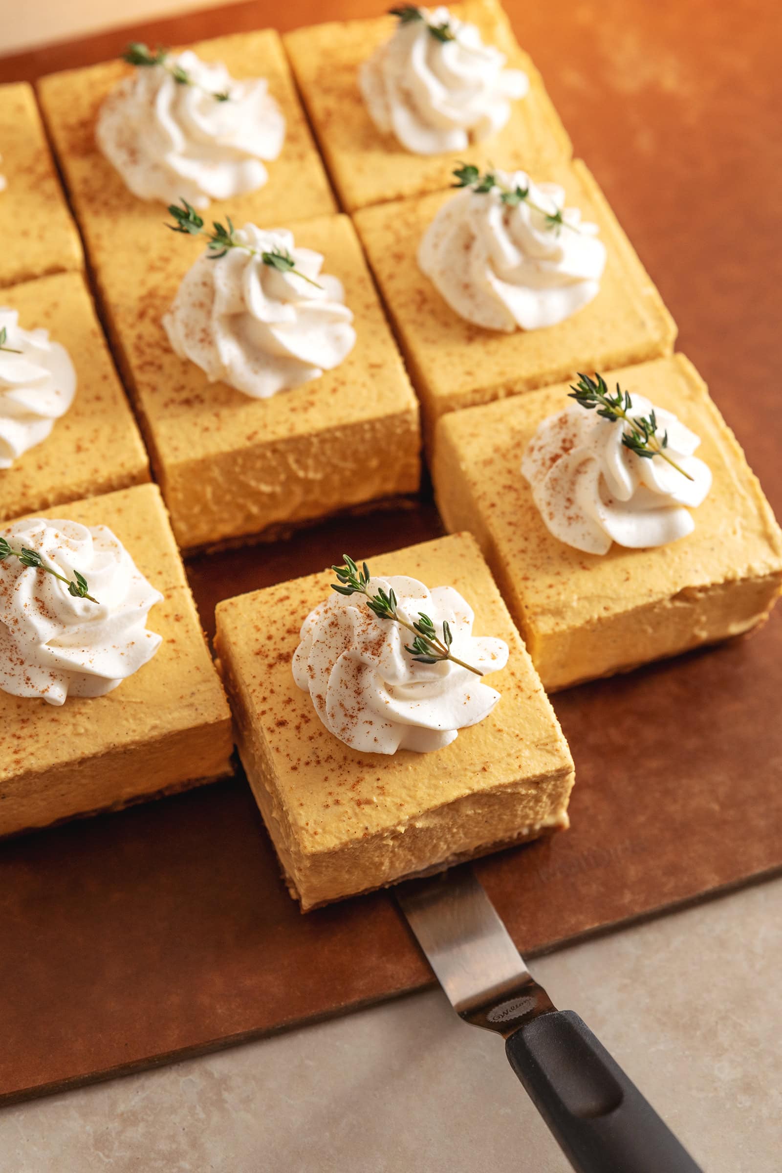 Pulling out a square of no-bake pumpkin cheesecake bar from the rest of the bars.