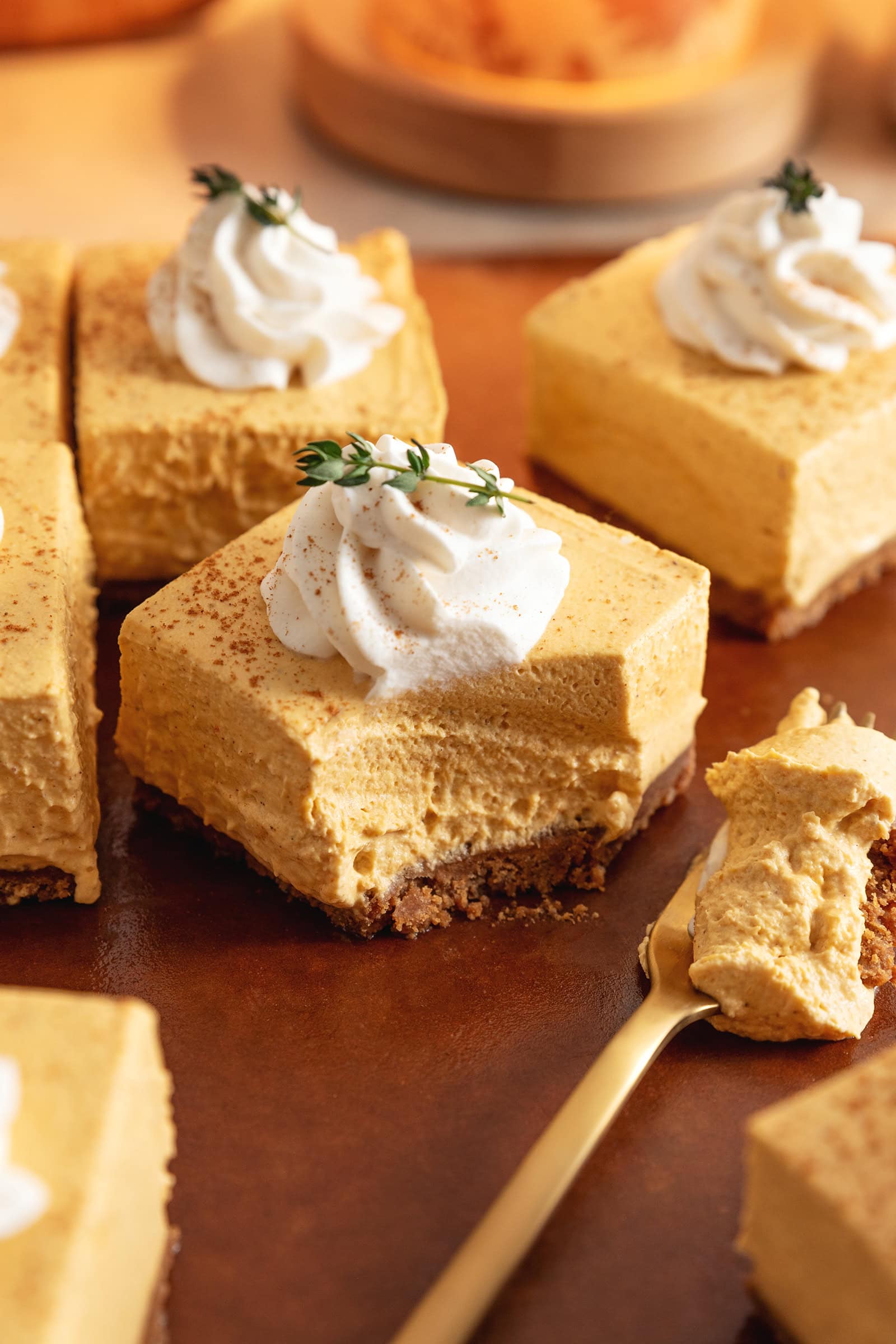 A no-bake pumpkin cheesecake bar with a scoop taken out of it to show the texture.