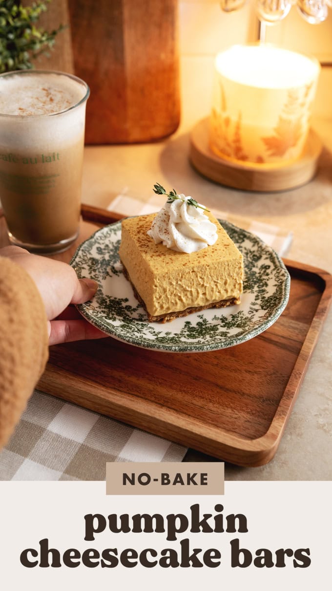 Hand placing a plate with a cheesecake bar onto a wooden platter.