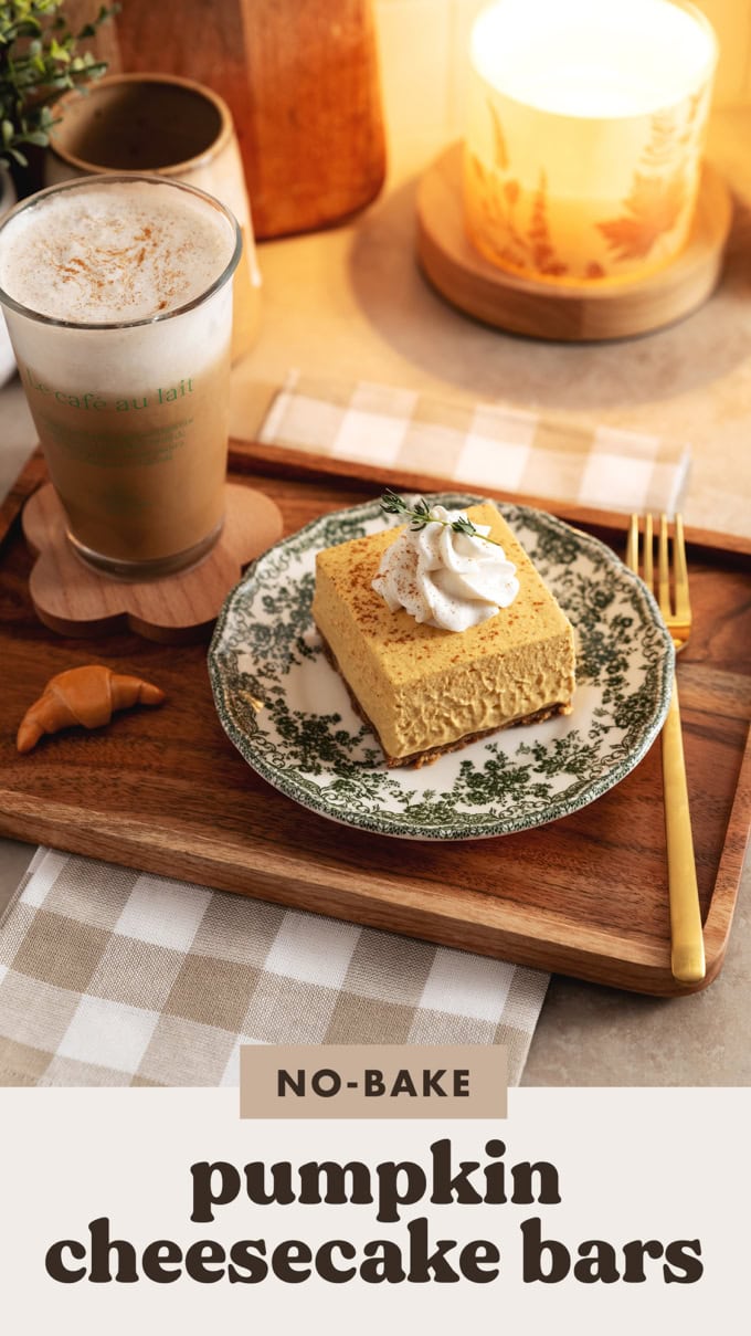A wooden platter with a latte and a pumpkin cheesecake bar.
