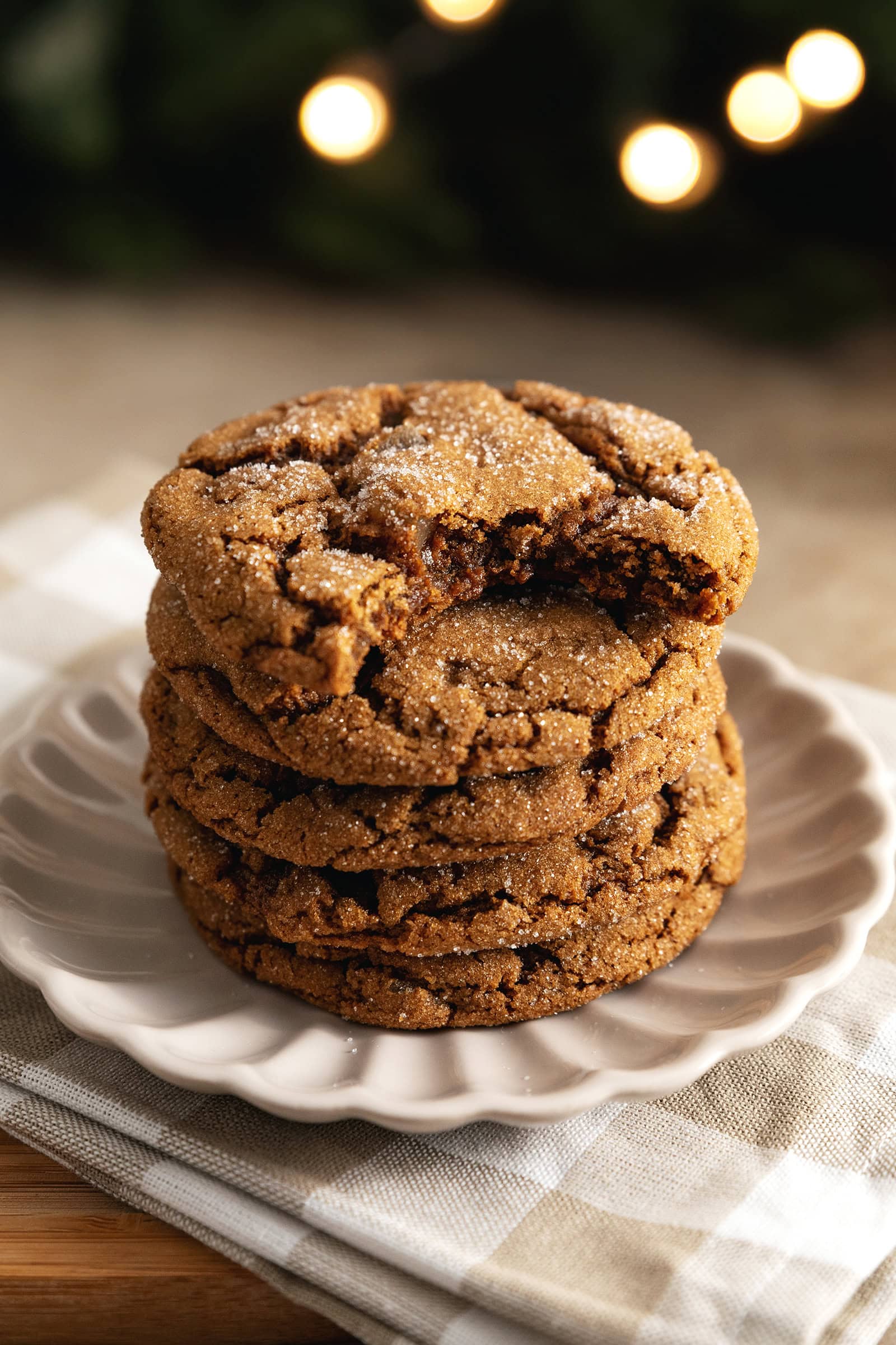A stack of chewy ginger cookies with a bite taken out of the cookie on top.