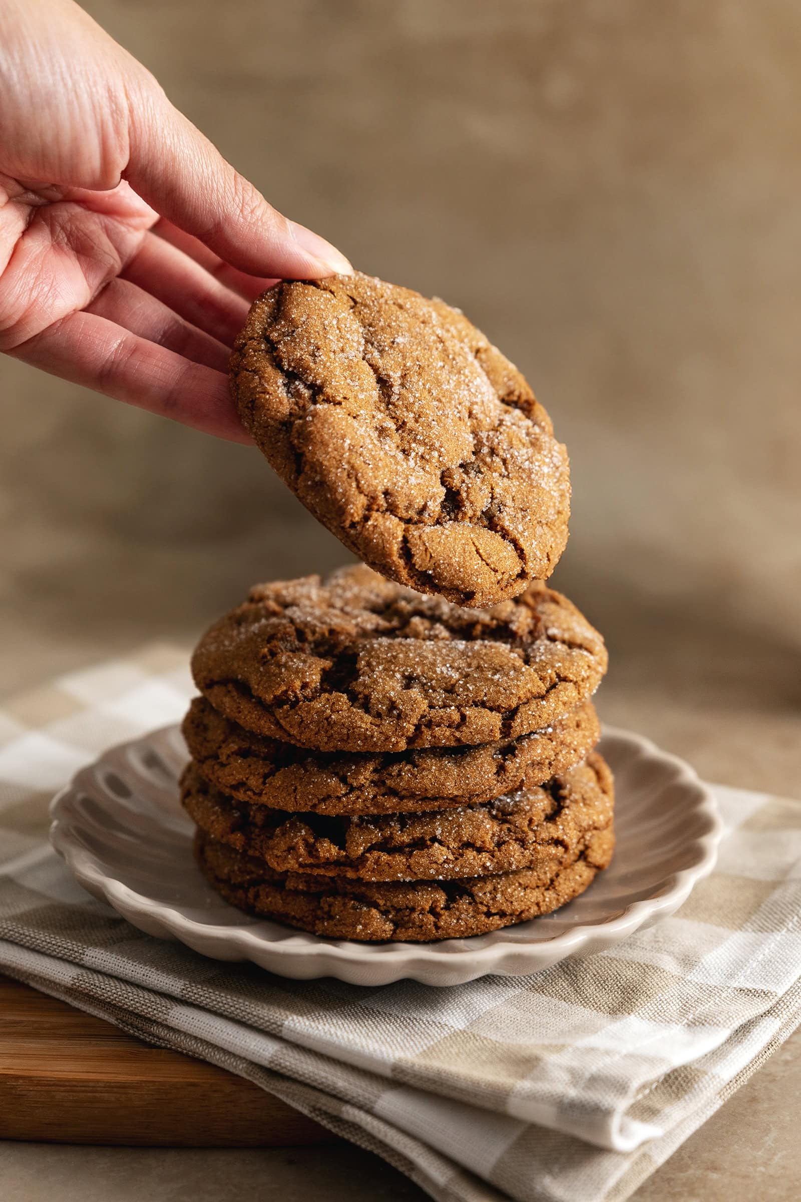 A hand placing a ginger cookie on top of a stack of cookies.