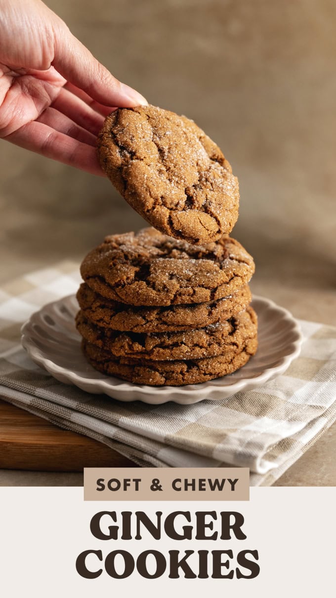 A hand placing a ginger cookie on top of a stack of cookies.