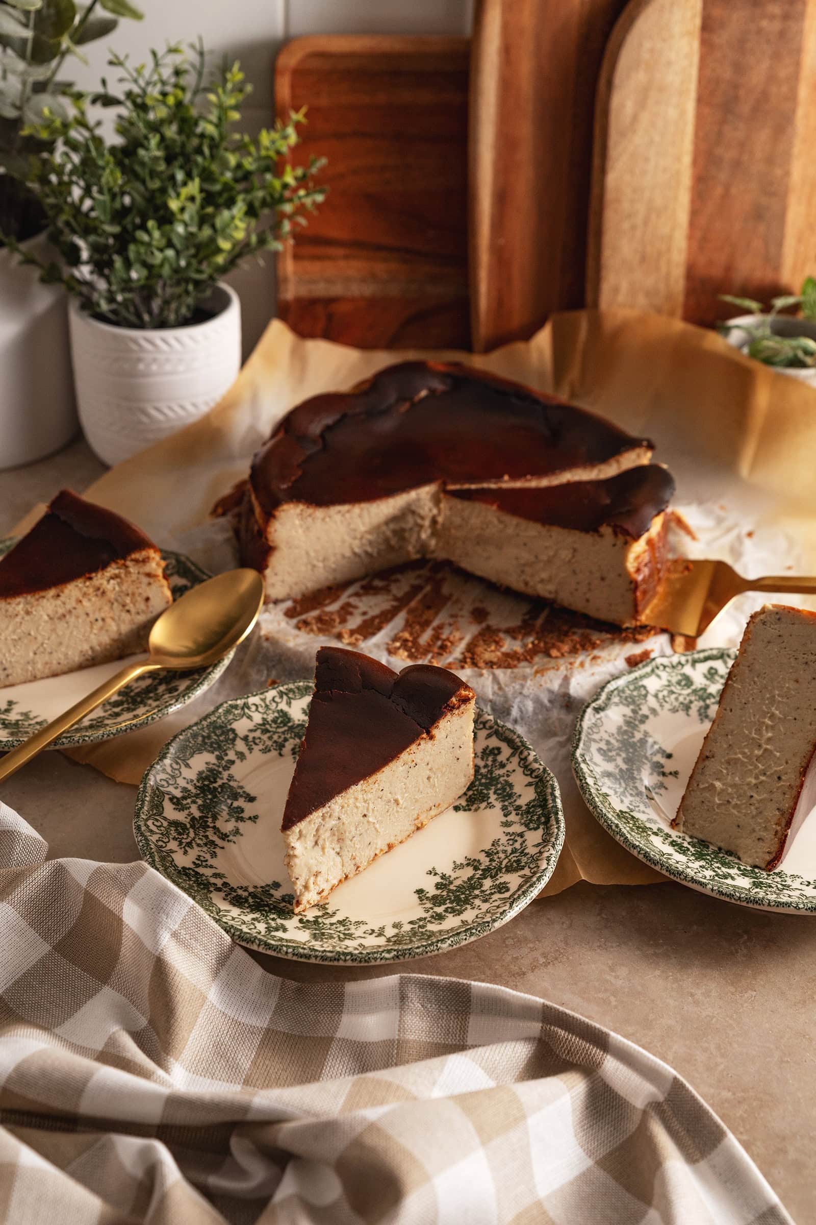 Slices of earl grey basque cheesecake on plates with the rest of the cheesecake in the back.