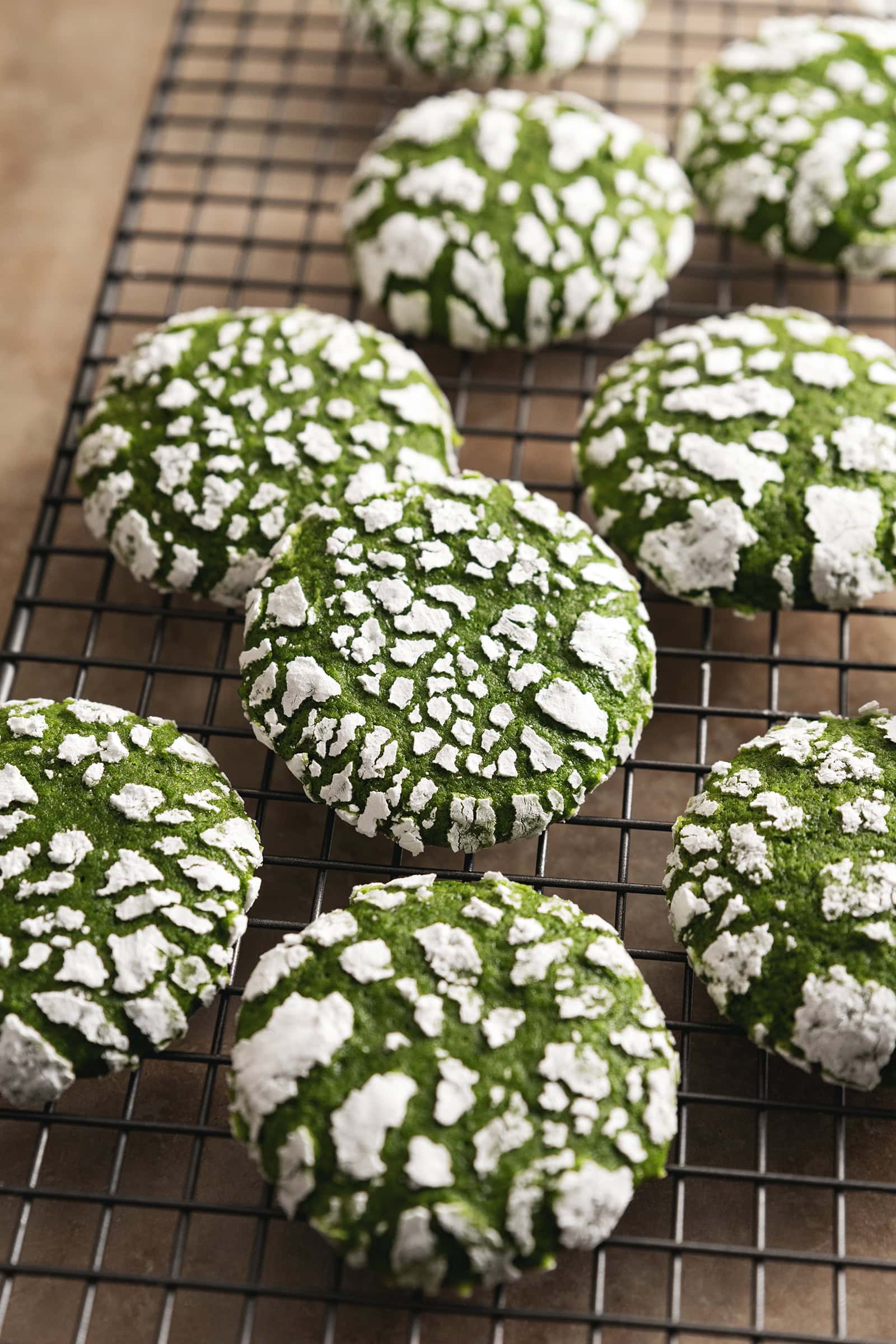 Matcha crinkle cookies scattered on a wire rack.