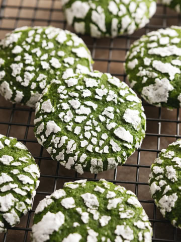 Matcha crinkle cookies scattered on a wire rack.