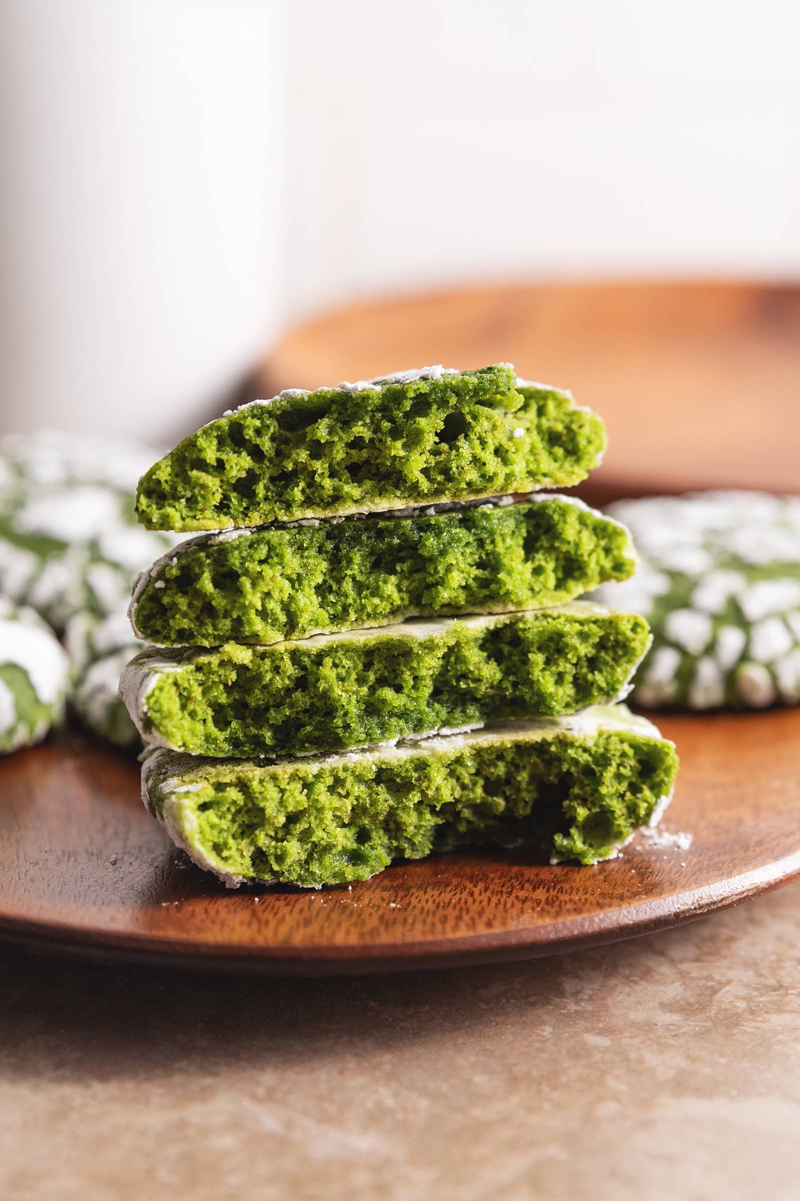 A stack of matcha crinkle cookies cut in half to show the fluffy texture inside.