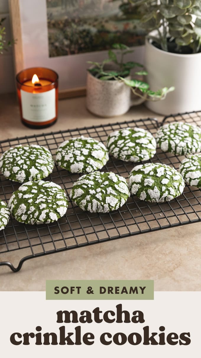 Matcha crinkle cookies lined up on a wire rack on a kitchen counter.