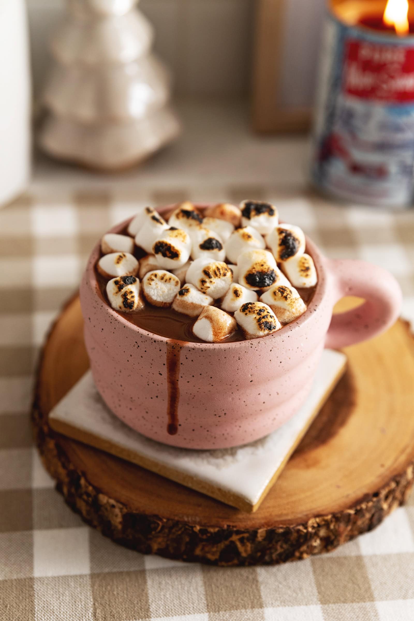 A mug of earl grey hot chocolate with toasted marshmallows on top and a drip down the side of the mug.