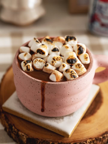 A mug of earl grey hot chocolate with toasted marshmallows on top and a drip down the side of the mug.