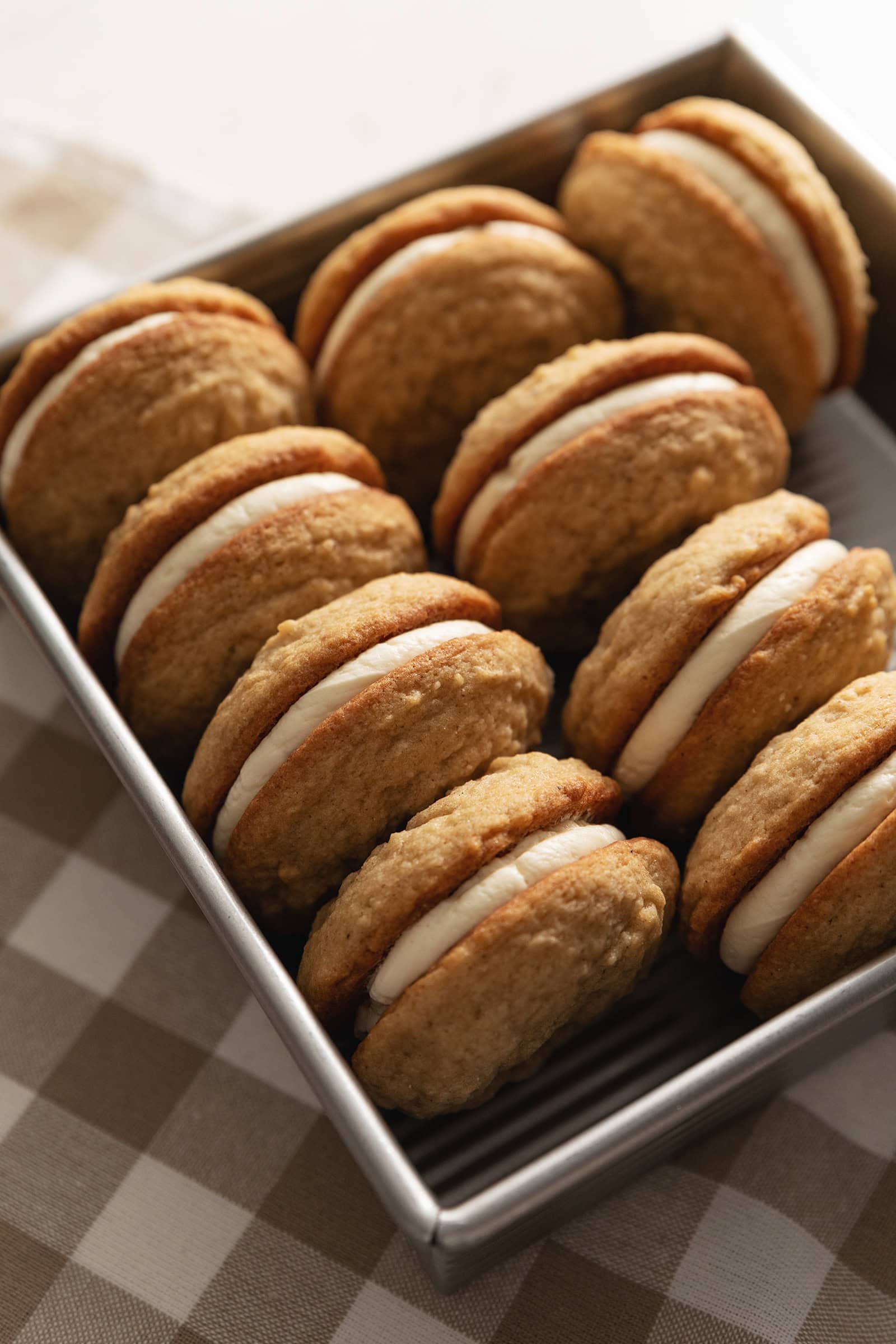 Eggnog sandwich cookies lined up in a baking pan.
