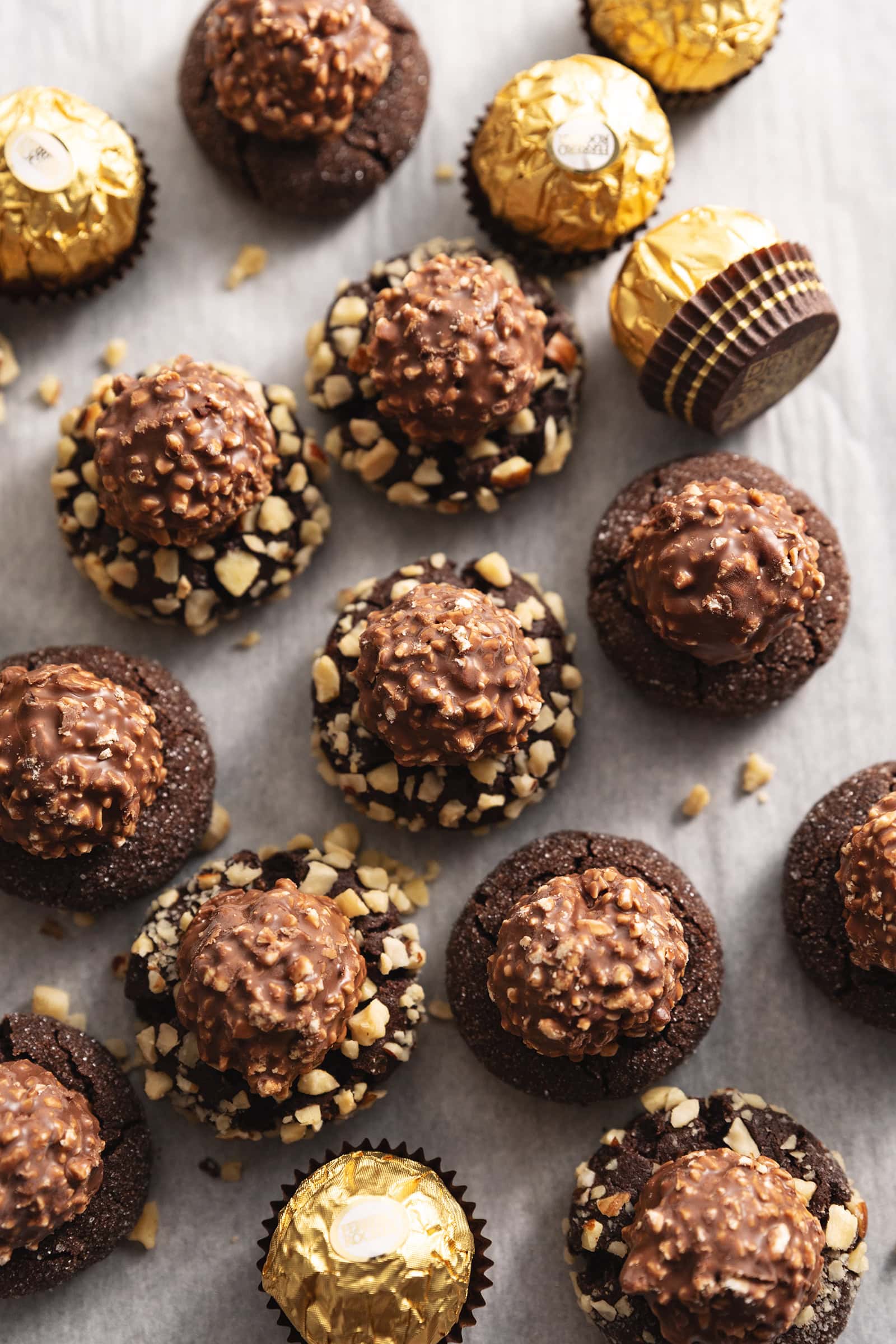 Overhead view of ferrero rocher blossom cookies scattered on parchment paper.