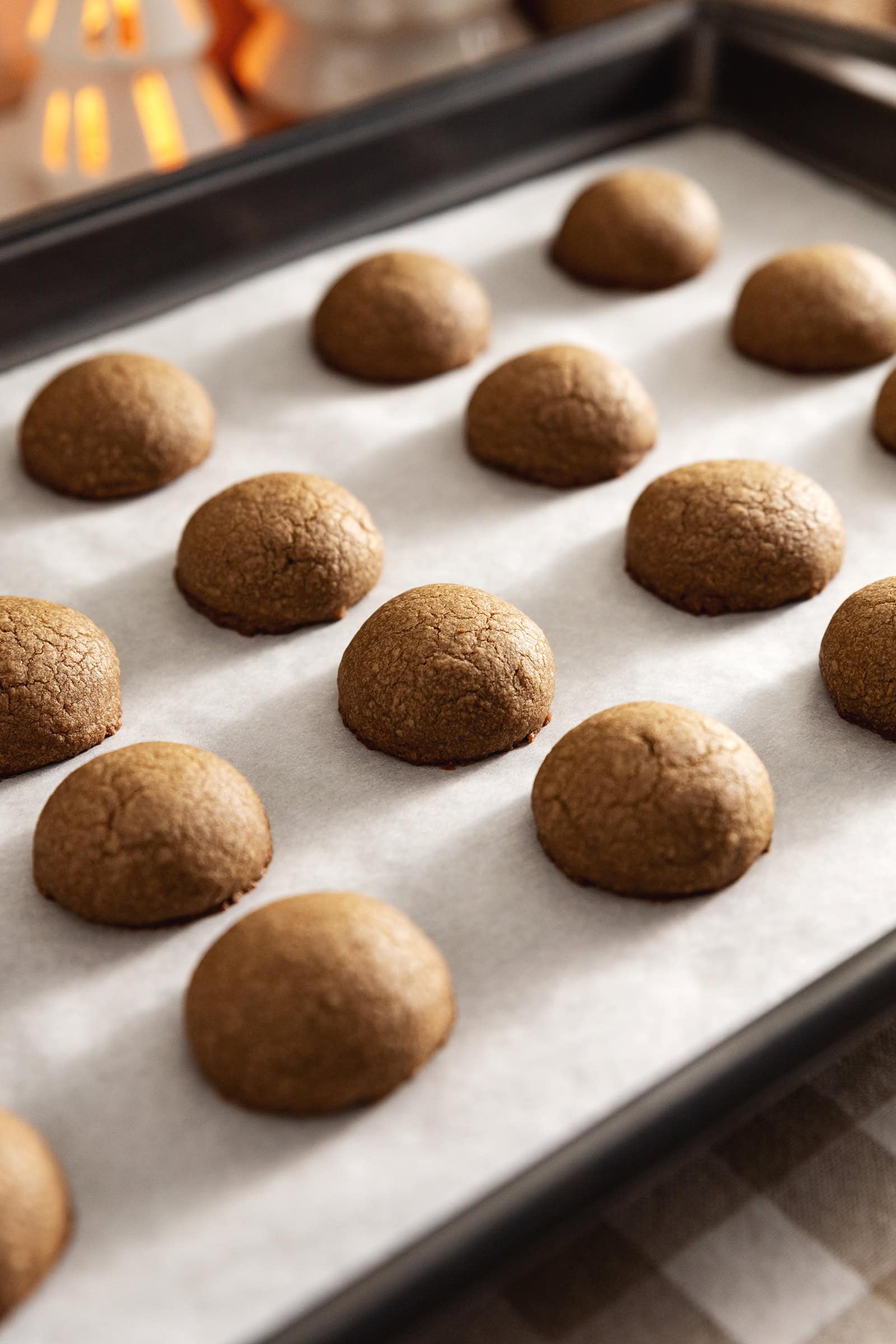 Hojicha cookies lined up on a baking tray before the powdered sugar coating.