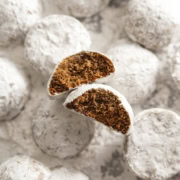 Two hojicha snowball cookies with bites taken out of them among several other cookies dusted with powdered sugar.