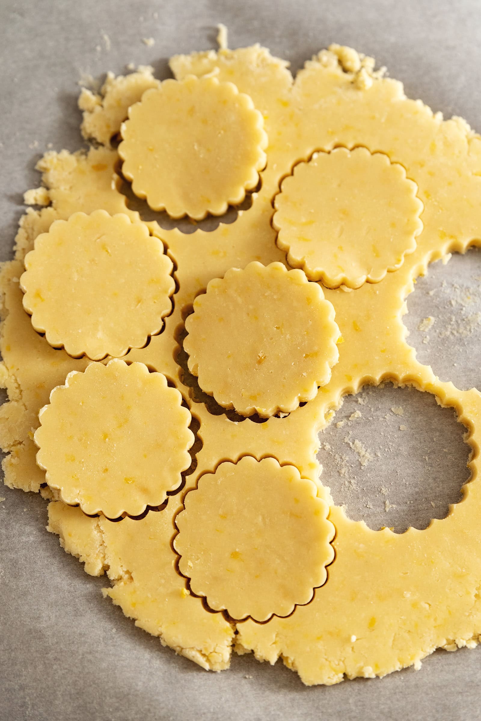 Scalloped discs cut out of a sheet of cookie dough.