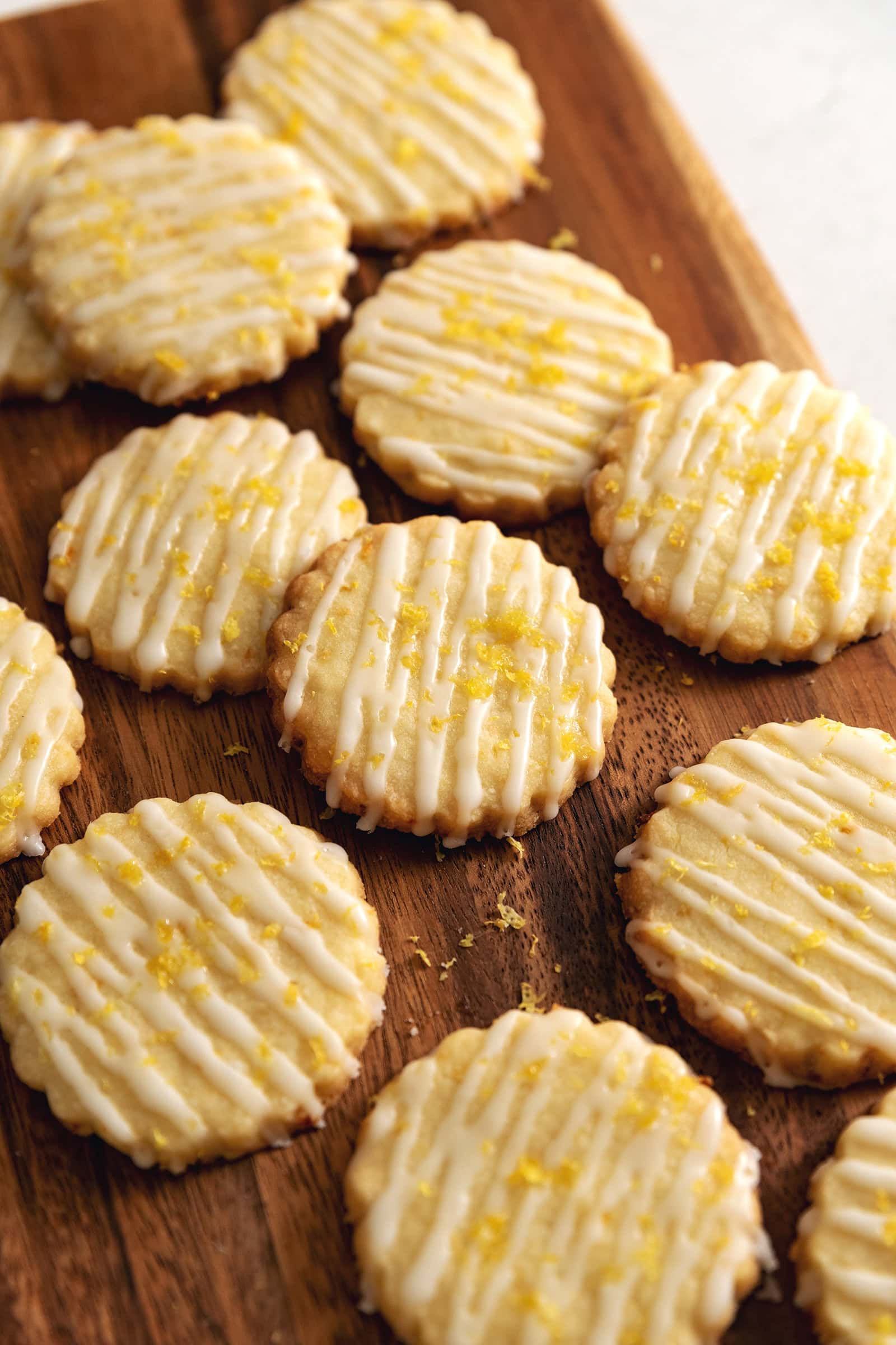 Lemon shortbread cookies scattered on a wooden platter.