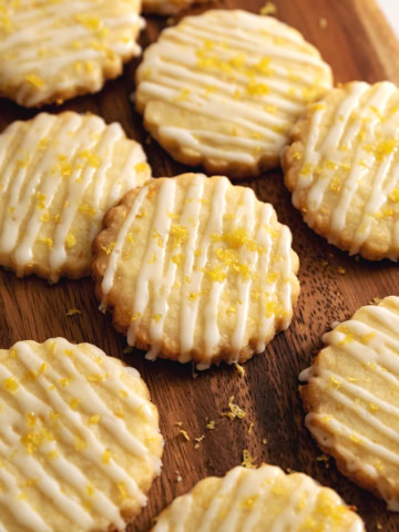 Lemon shortbread cookies scattered on a wooden platter.