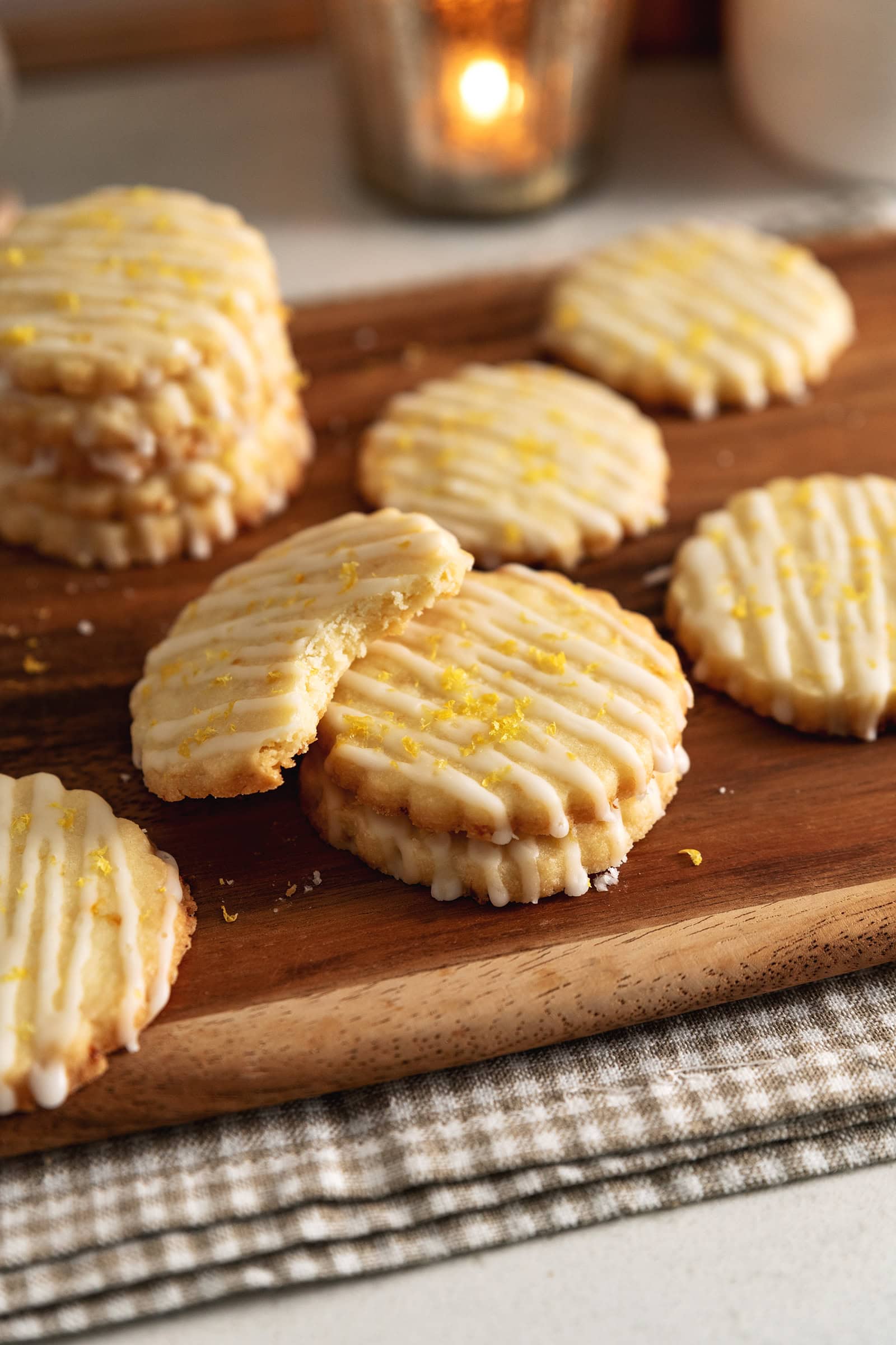 A lemon shortbread cookie with a bite taken out of it leaning against a stack of cookies.