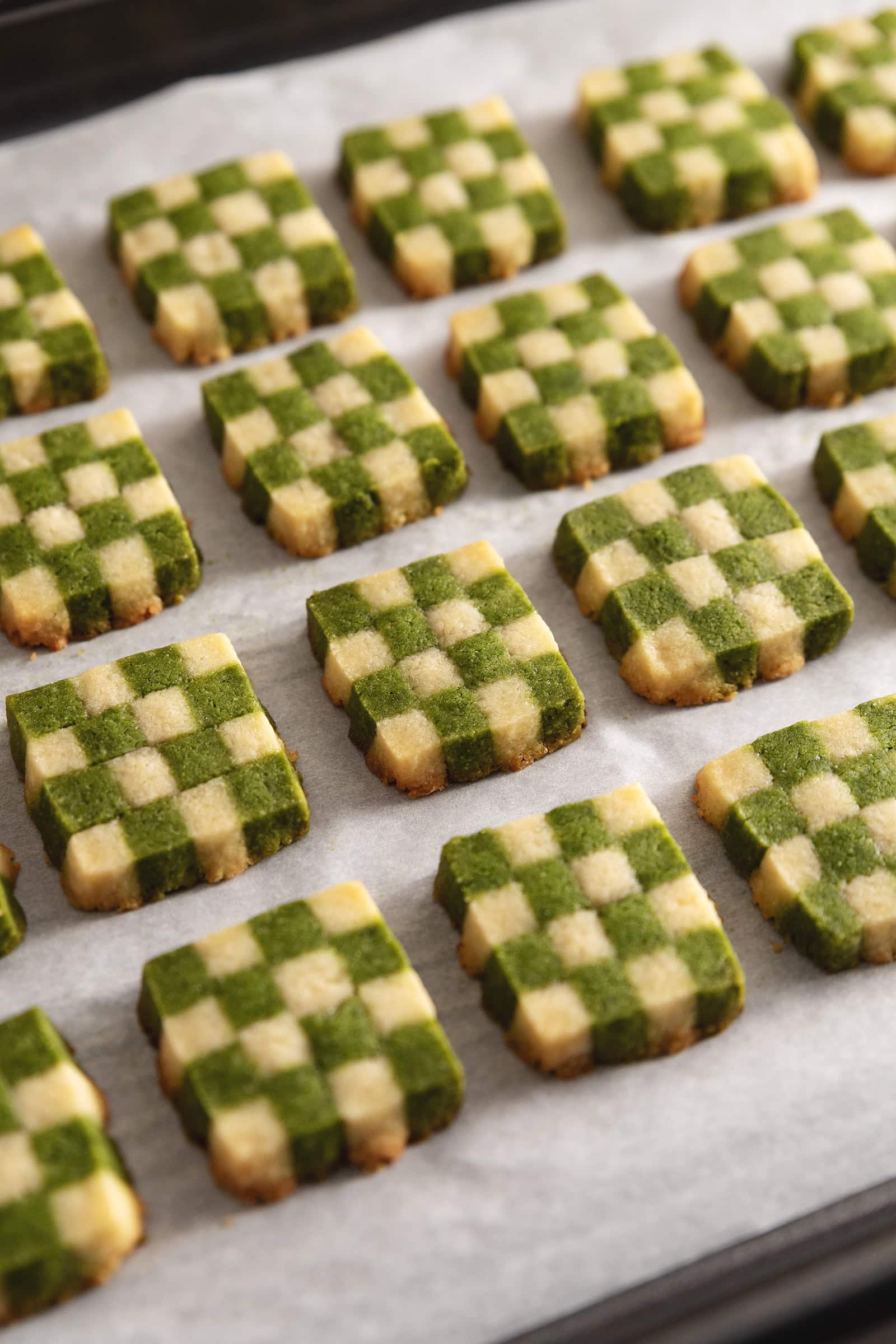 Matcha checkerboard cookies lined up on a baking sheet.