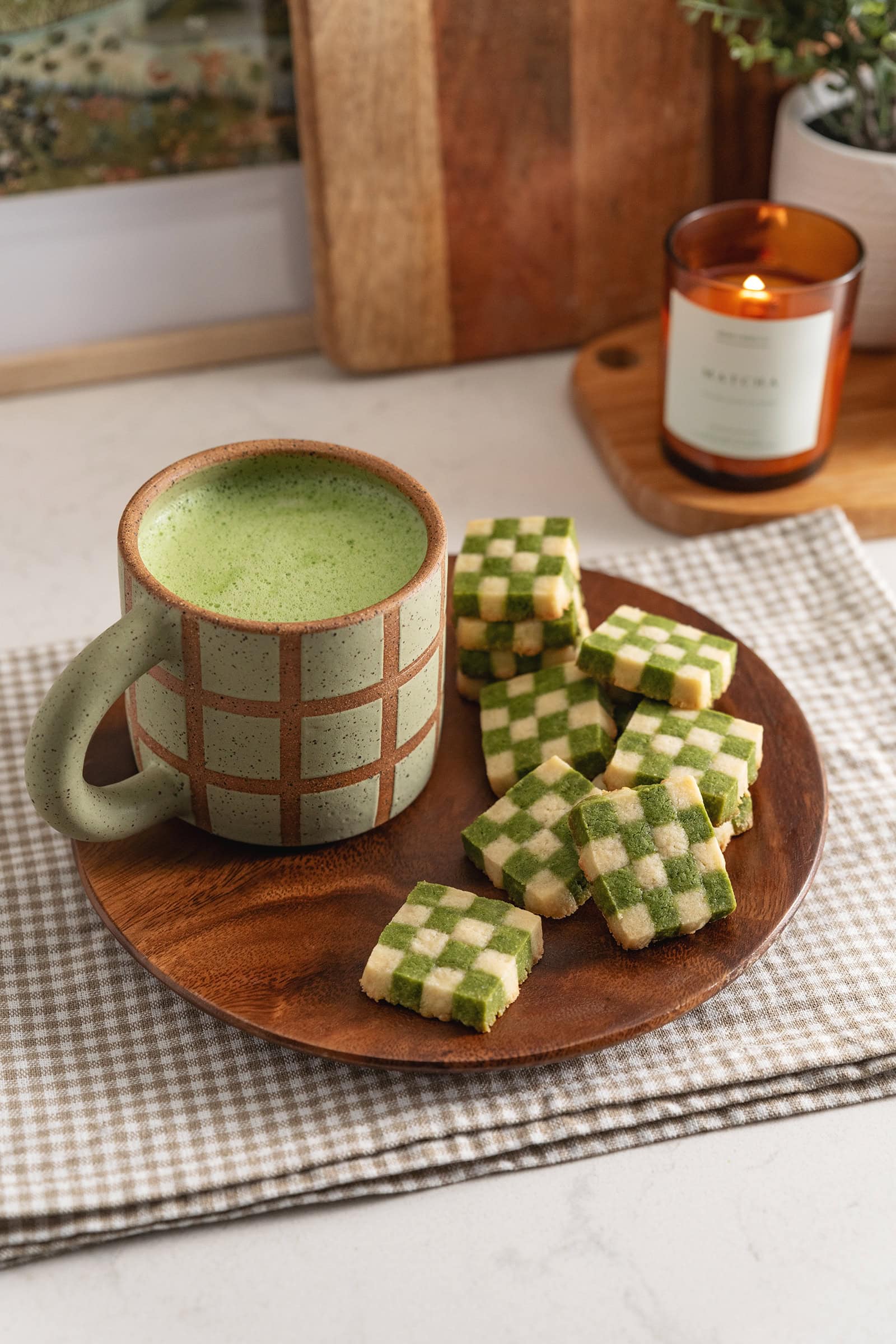 Matcha checkerboard cookies on a plate with a mug of matcha latte.