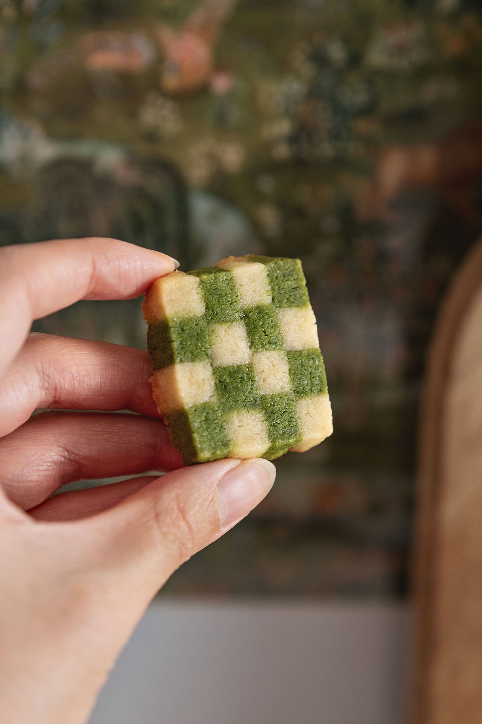 Hand holding a matcha checkerboard cookie to show the checkerboard pattern.