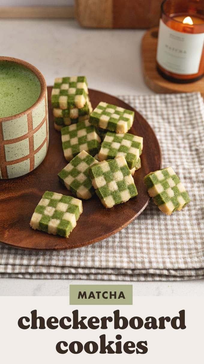 Matcha checkerboard cookies piled on a plate next to a mug of matcha latte.