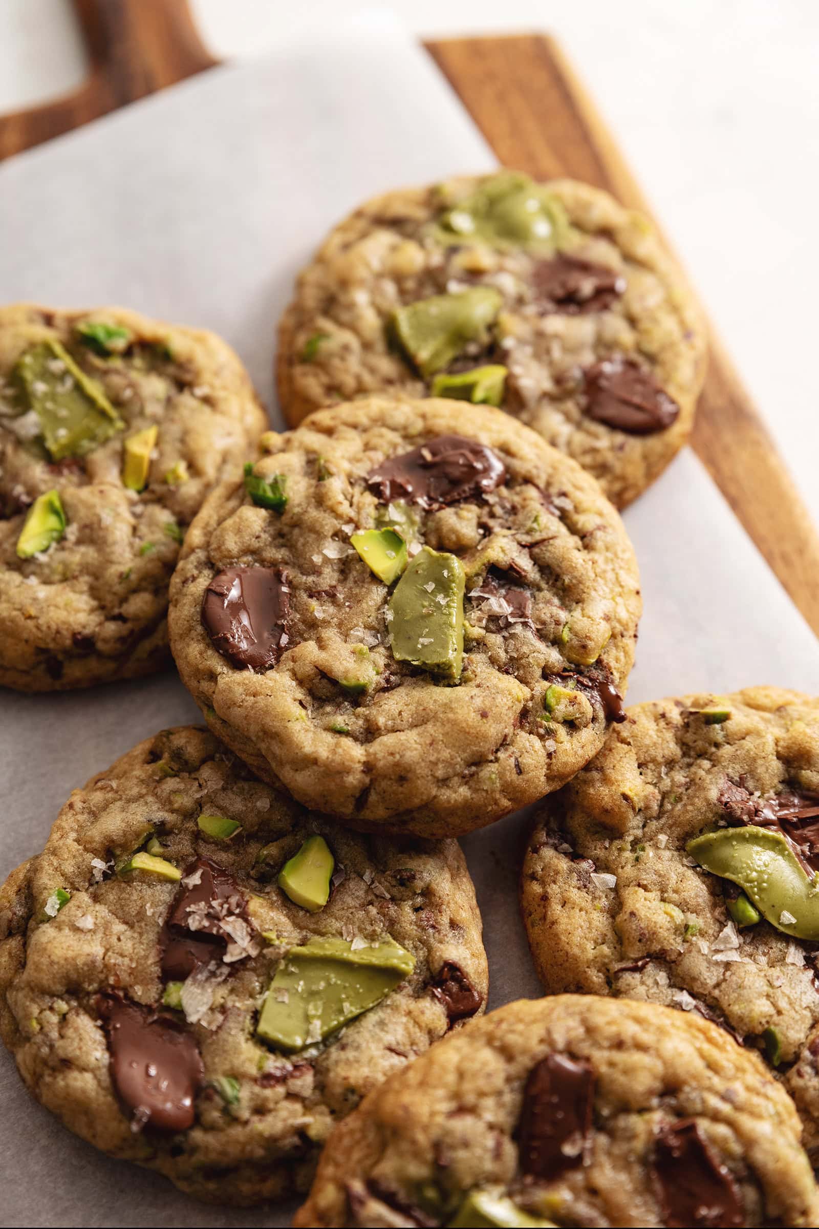 Pistachio cream cookies stacked on a wooden board.
