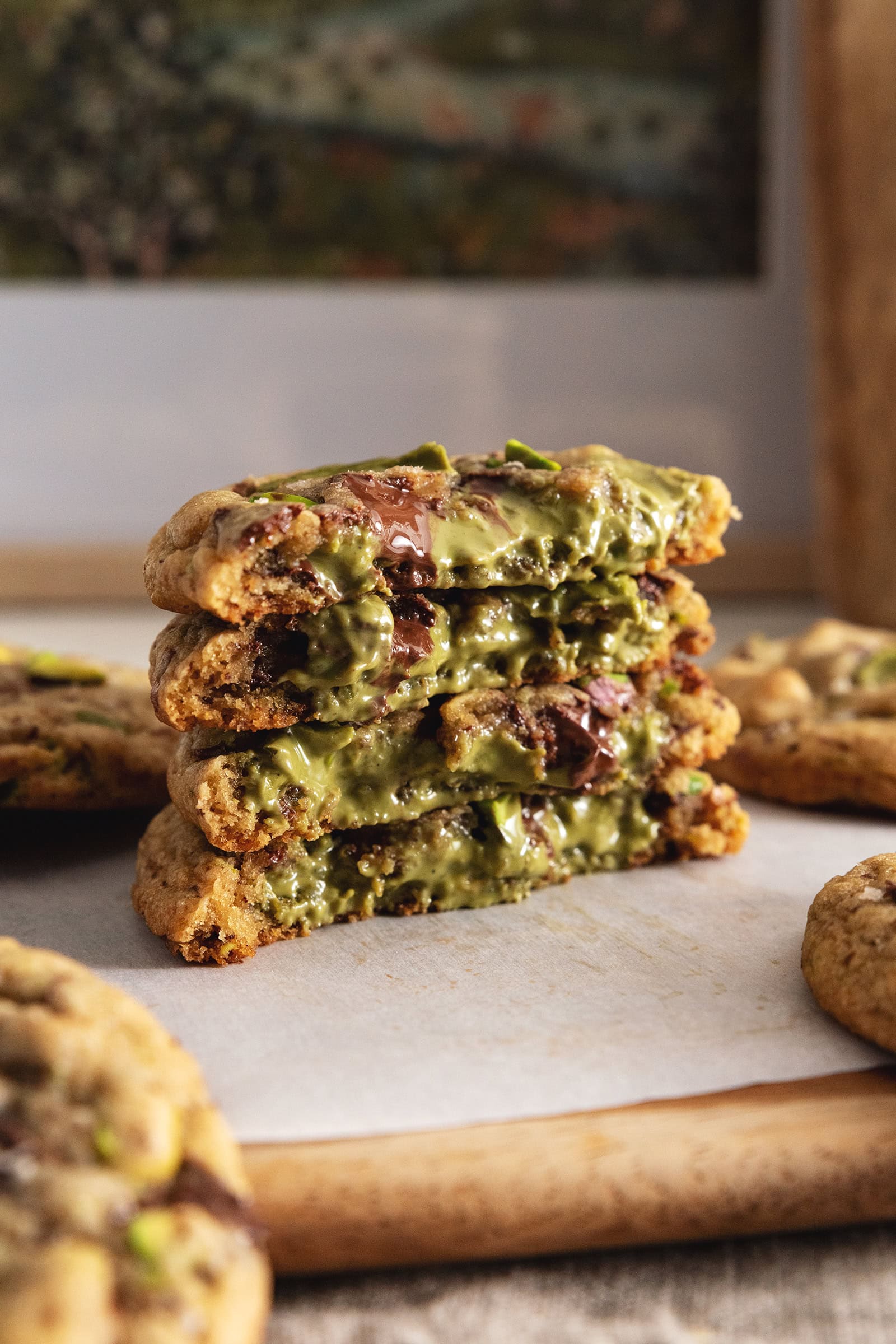 A stack of pistachio cream cookies cut in half to show the pistachio filling inside.