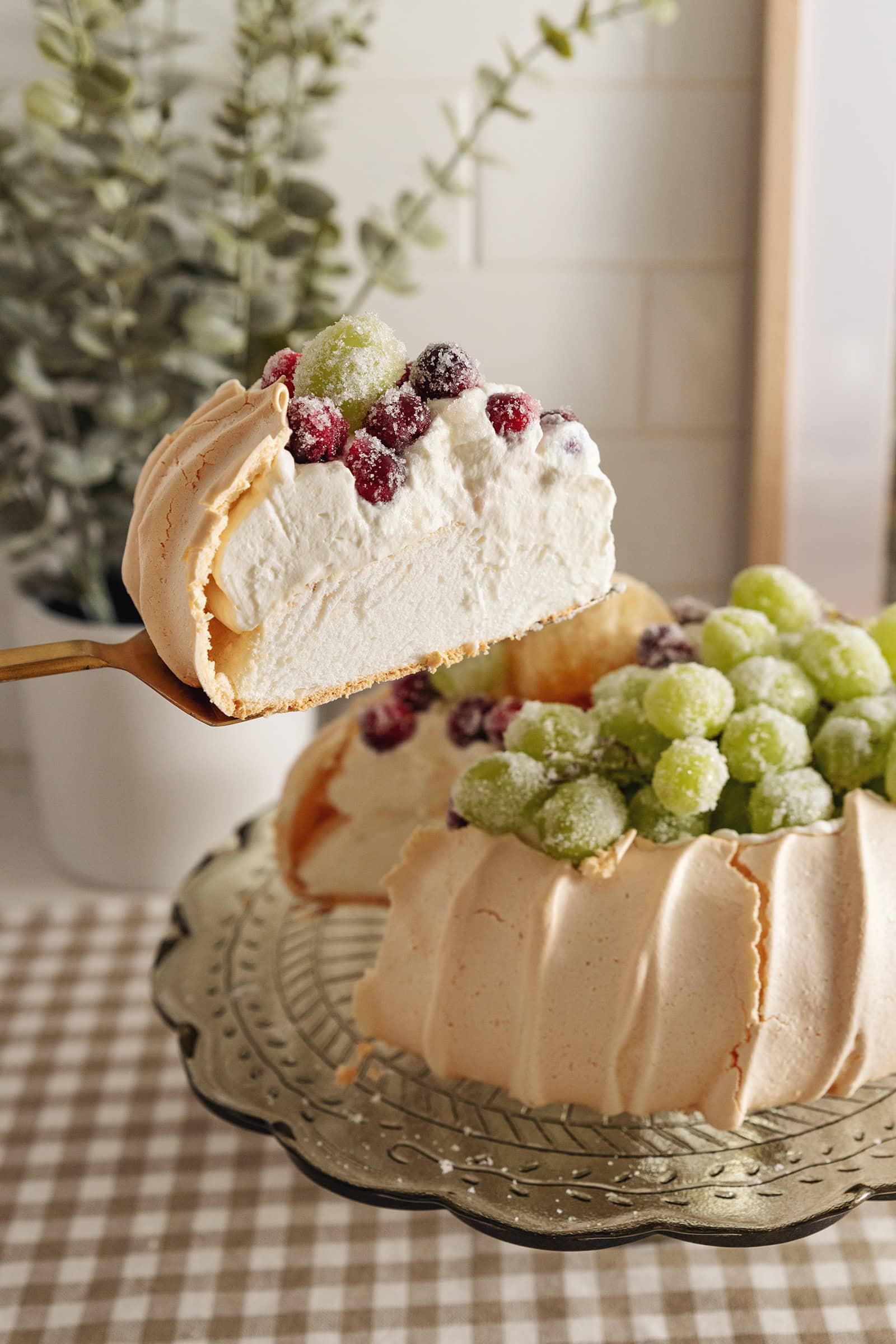Lifting a slice of sugared fruit pavlova from the rest of the cake to show the texture inside.