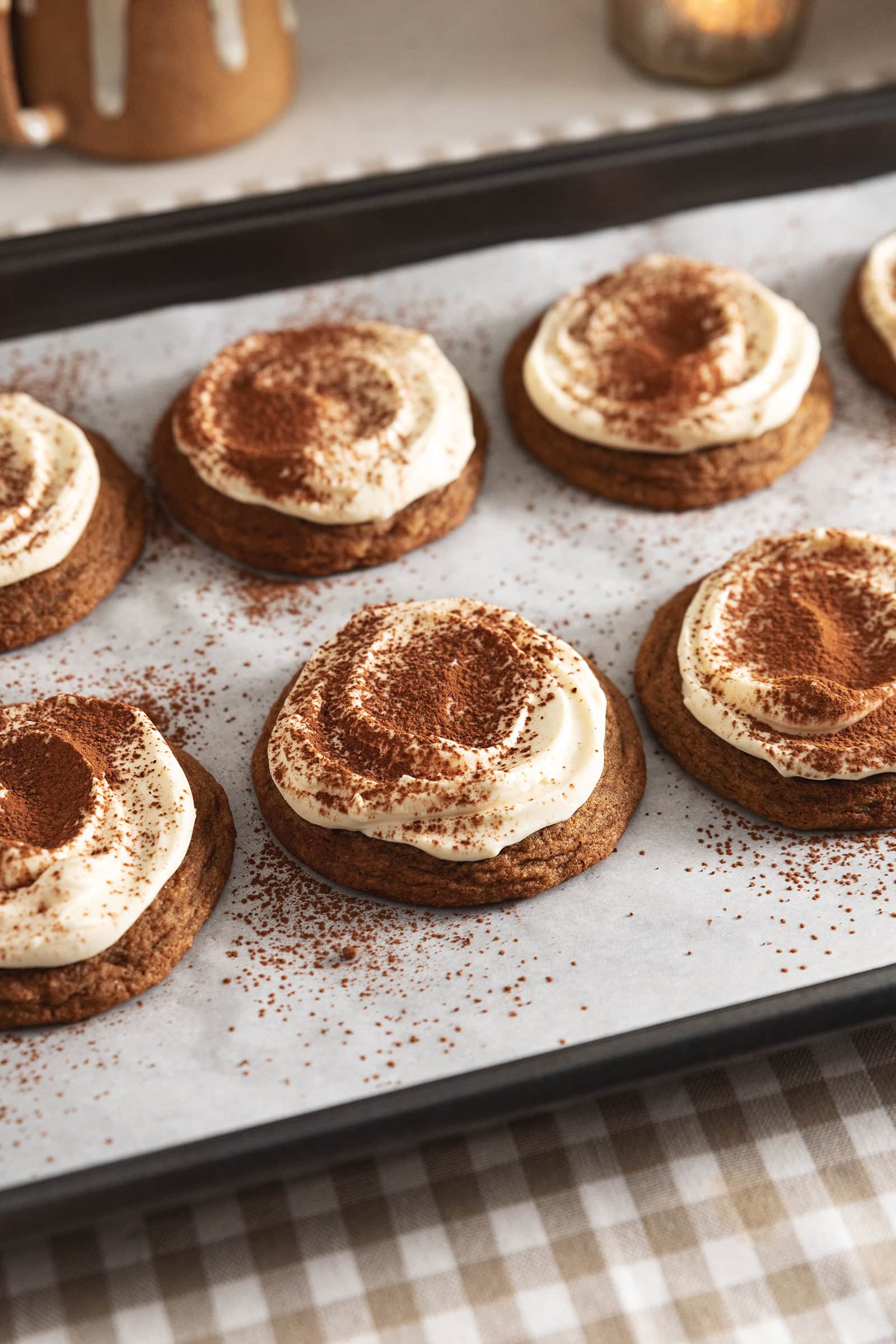 Tiramisu cookies dusted with cocoa powder and lined up on a baking tray.