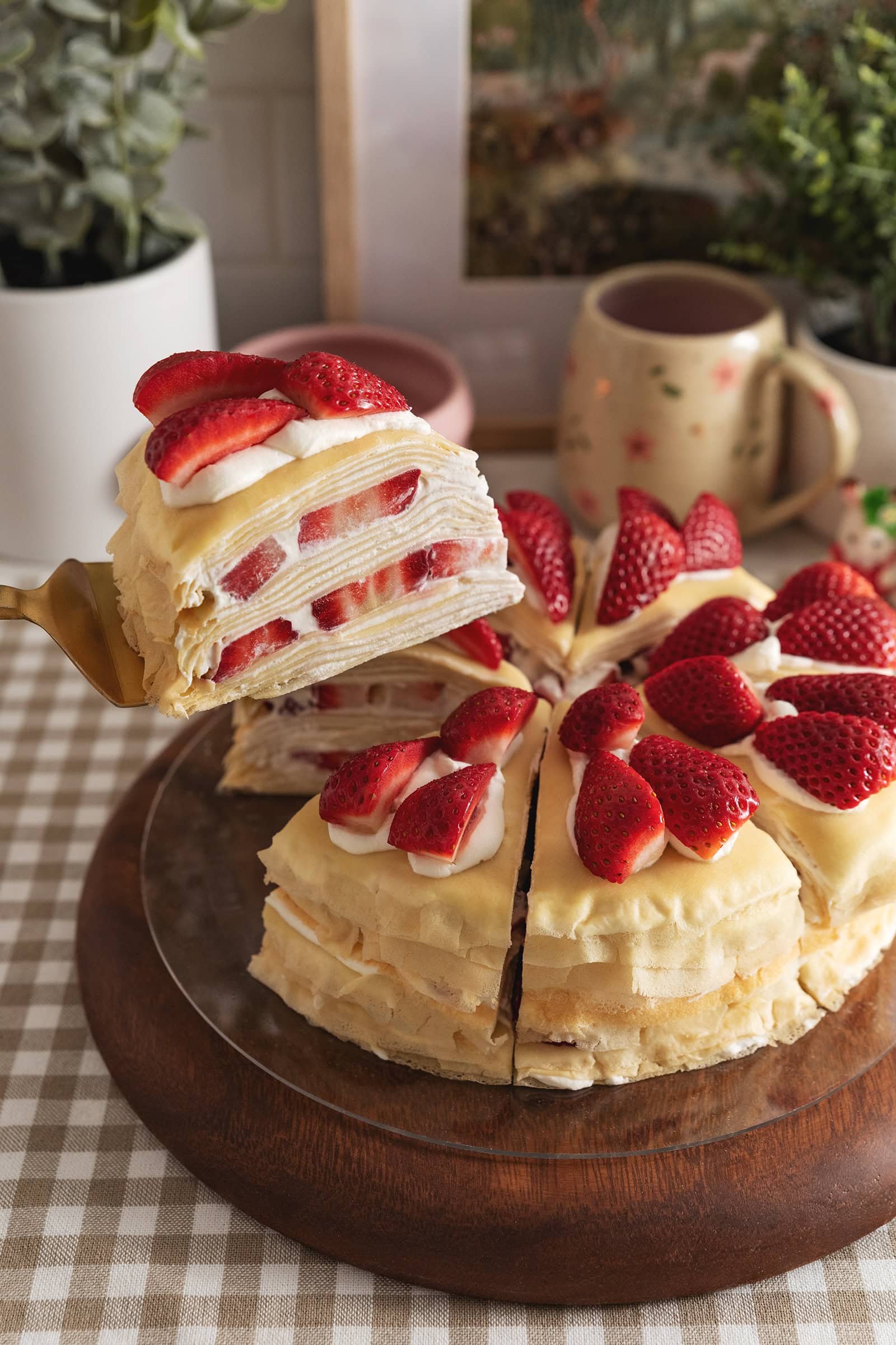 Lifting a slice of strawberry crepe cake above the the rest of the slices.