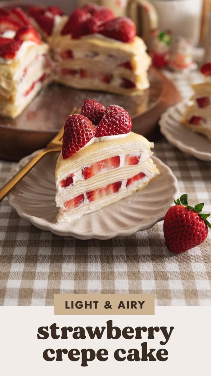 A slice of strawberry crepe cake on a plate with layers of crepes, whipped cream, and strawberry slices.