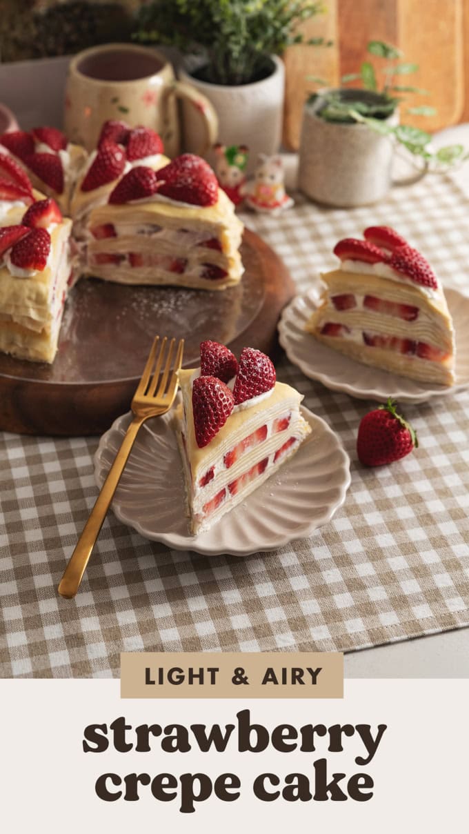 Two slices of strawberry crepe cake on plates in front of the rest of the cake.