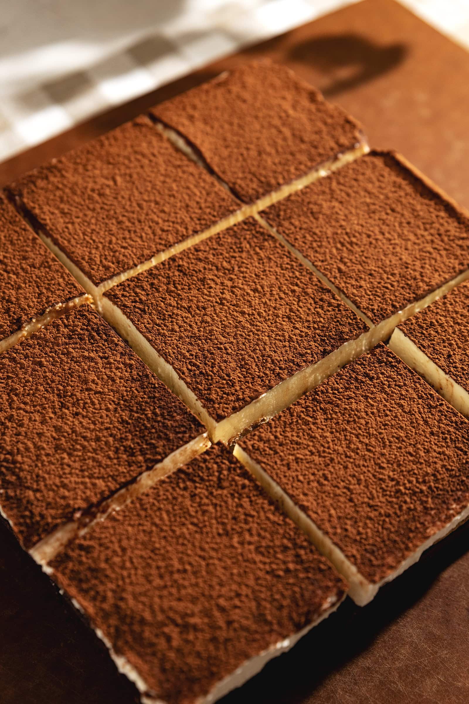 Tiramisu brownies sliced into squares with cocoa powder sprinkled on top.