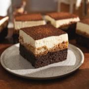 A tiramisu brownie on a speckled plate in front of other brownies.